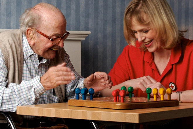 Das Bild zeigt eine BRK-Mitarbeiterin und einen älteren Herr beim Spielen. 