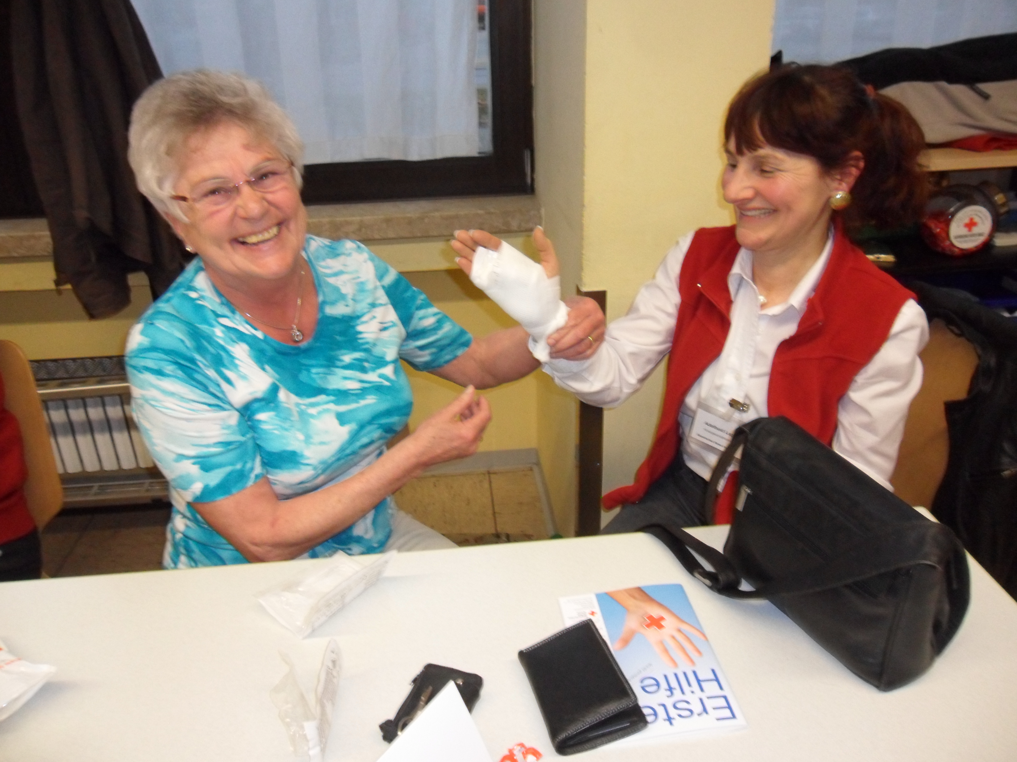 Bild zeigt Senioren, die im Kurs von Ersthelferin mit Armverband versorgt wird.