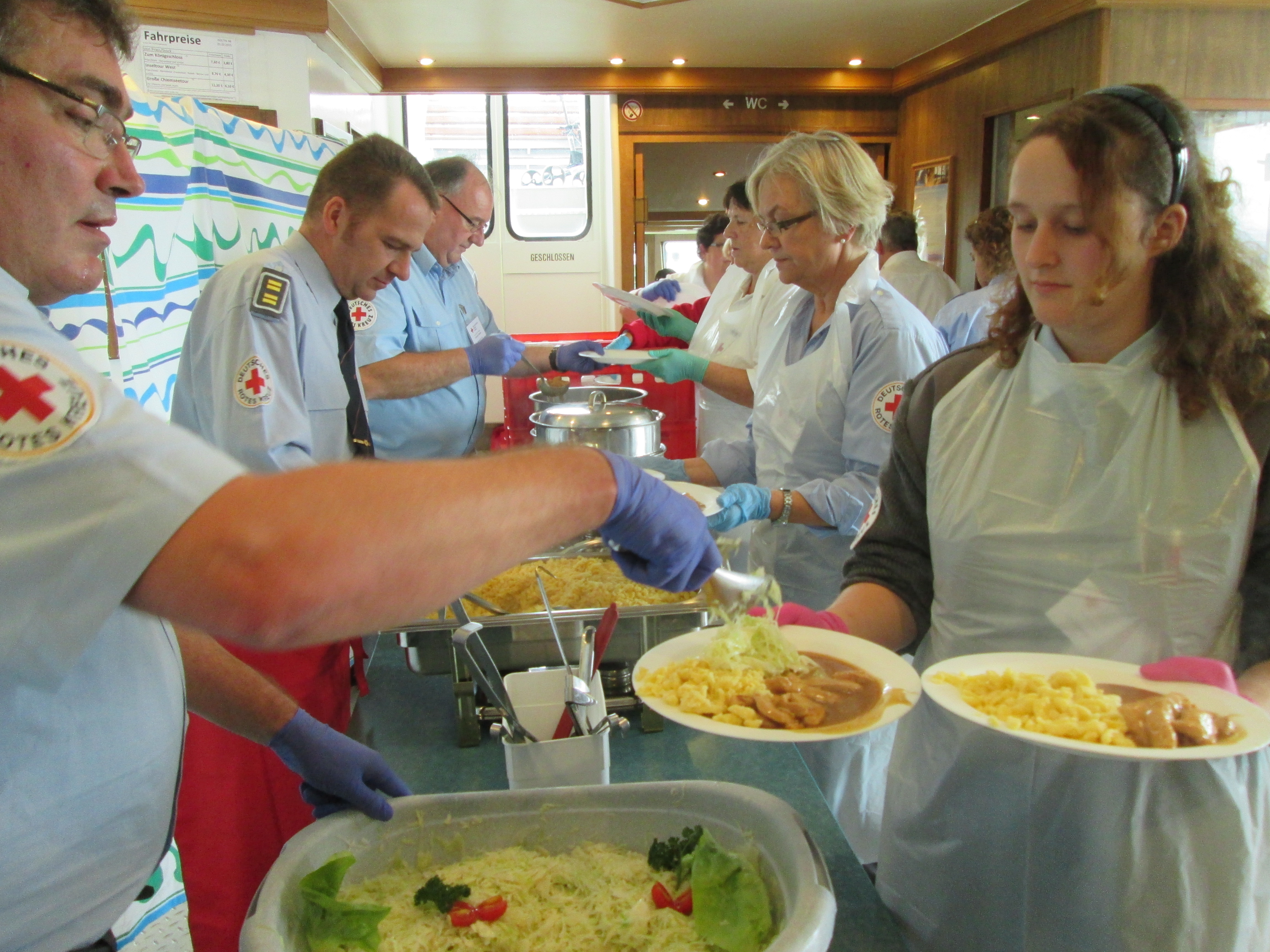 Rotkreuz-Helferinnen und -Helfer, die den Ausflügsgästen das Mittagessen servieren
