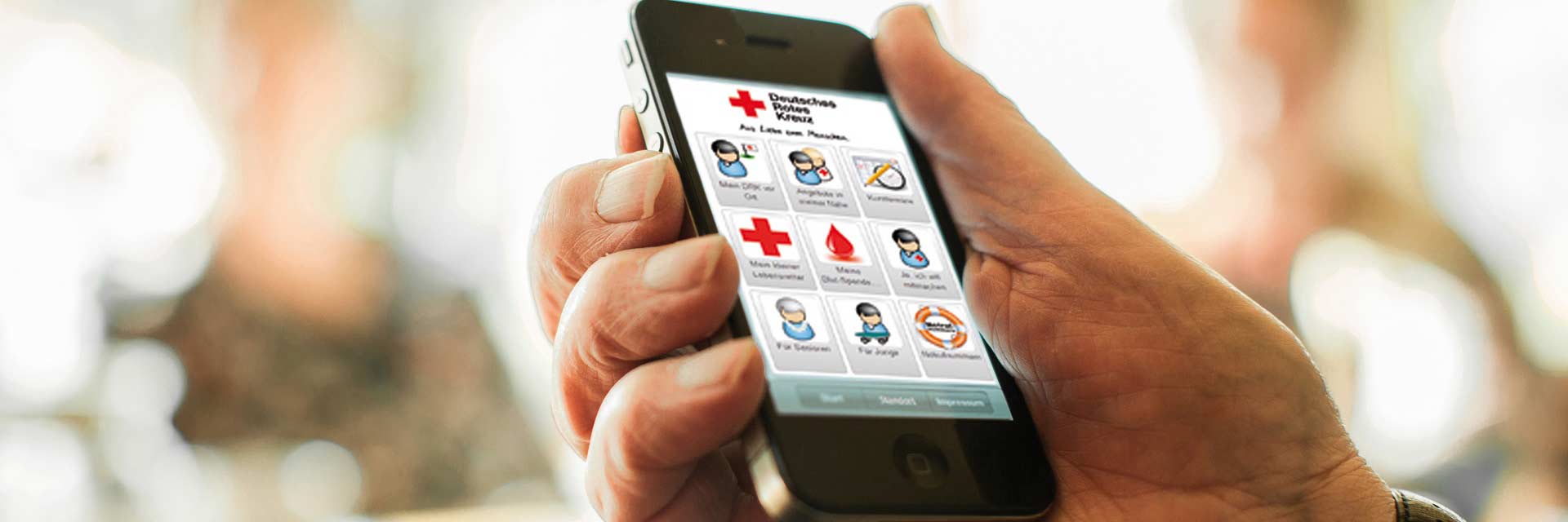 Eine Hand hält ein Smartphone, auf dem die Rotkreuz-App aktiv ist.