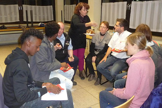 das Foto zeigt Rotkreuzmitarbeiter und junge Flüchtlinge im Stuhlkreis bei einer Veranstaltung