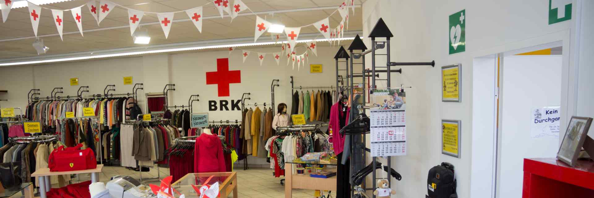 Das Bild zeigt die Ladeneinrichtung des Kleiderladen Wasserburg mit Dekoration des BRK.