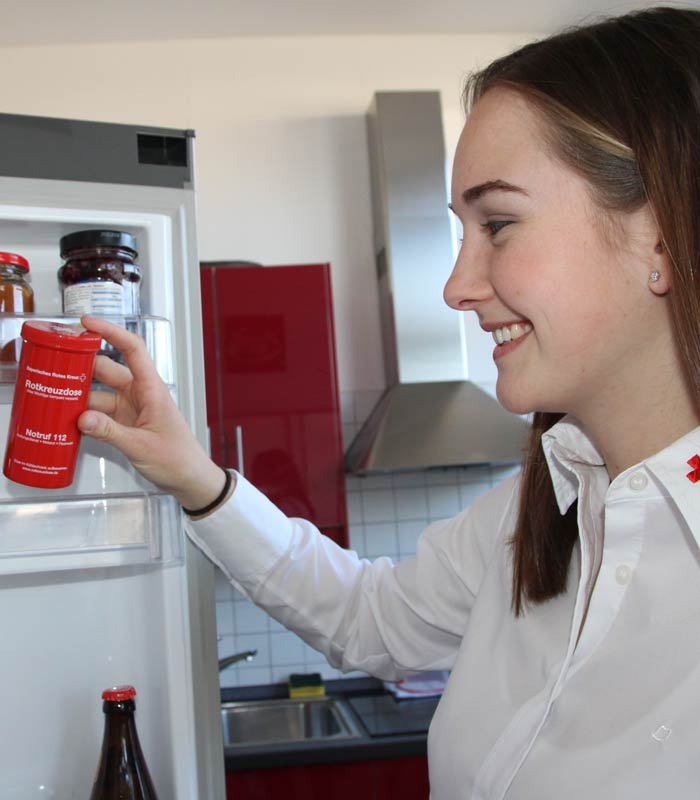 Rotkreuzmitarbeiterin mit Rotkreuzdose am Kühlschrank